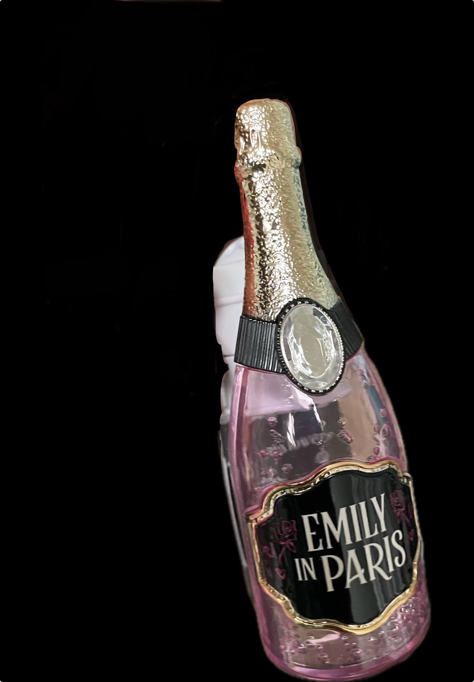 Pink bottle-shaped ornament with 'Emily in Paris' label on a black background