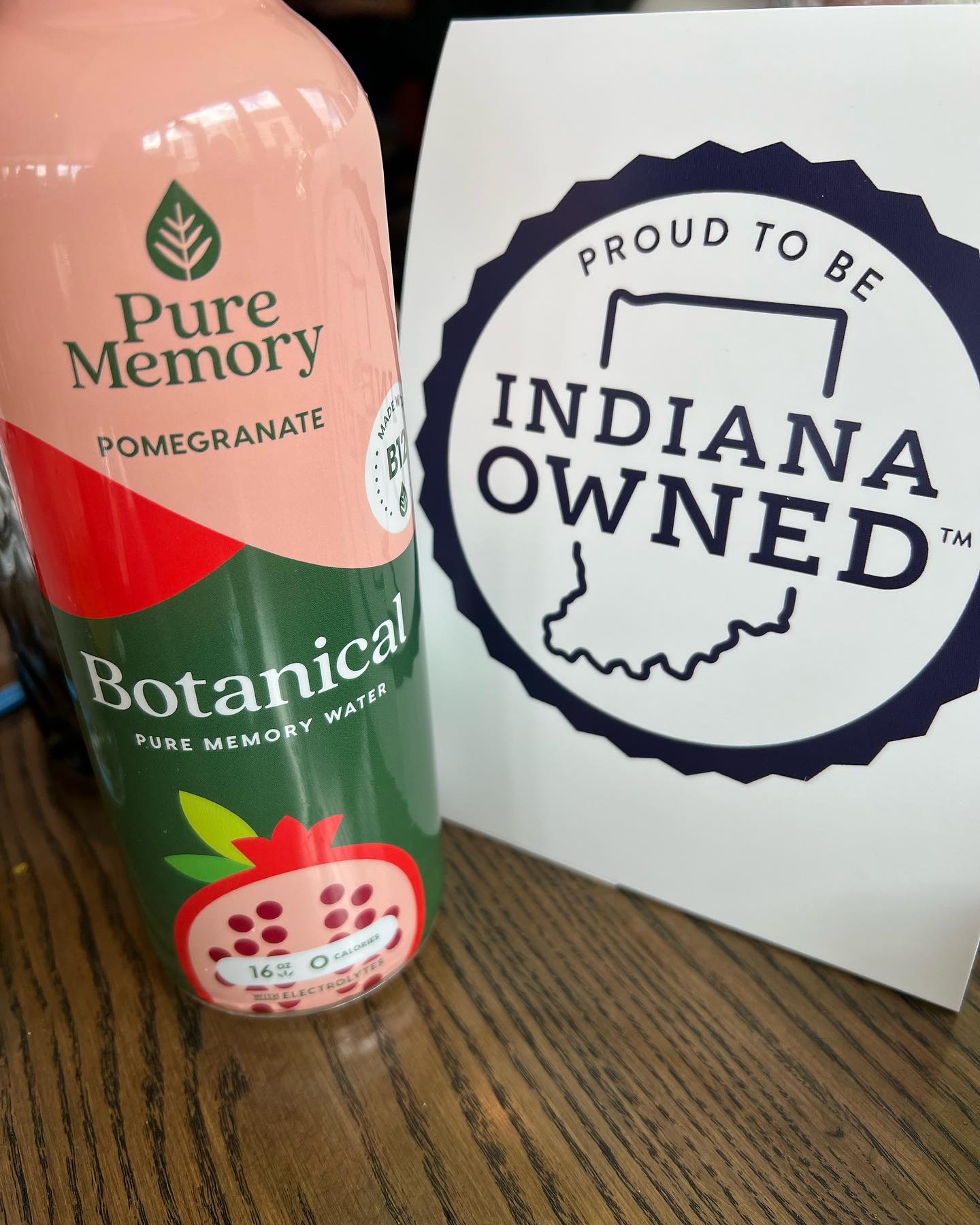 Bottle of Pure Memory Pomegranate Botanical water next to a sign saying 'Proud to be Indiana Owned'.