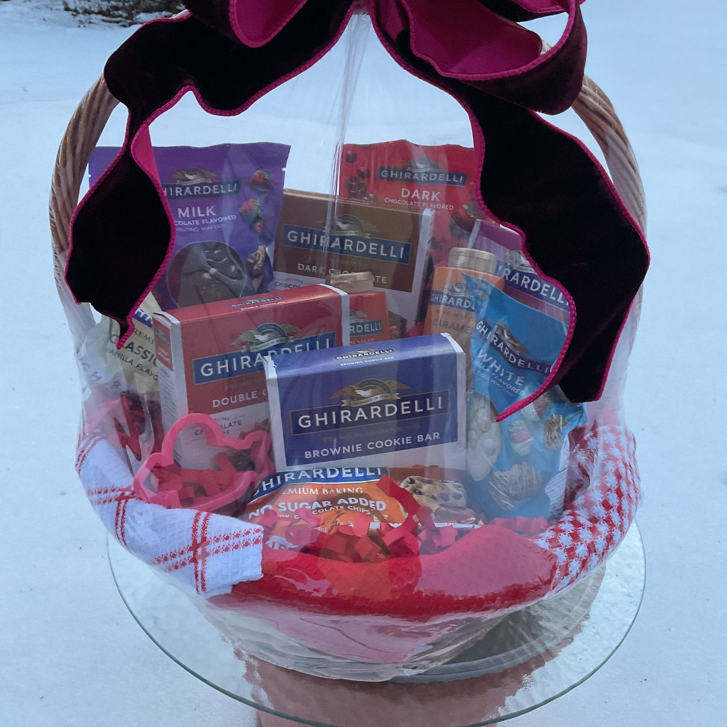 Ghirardelli chocolate gift basket with a pink bow on a white surface