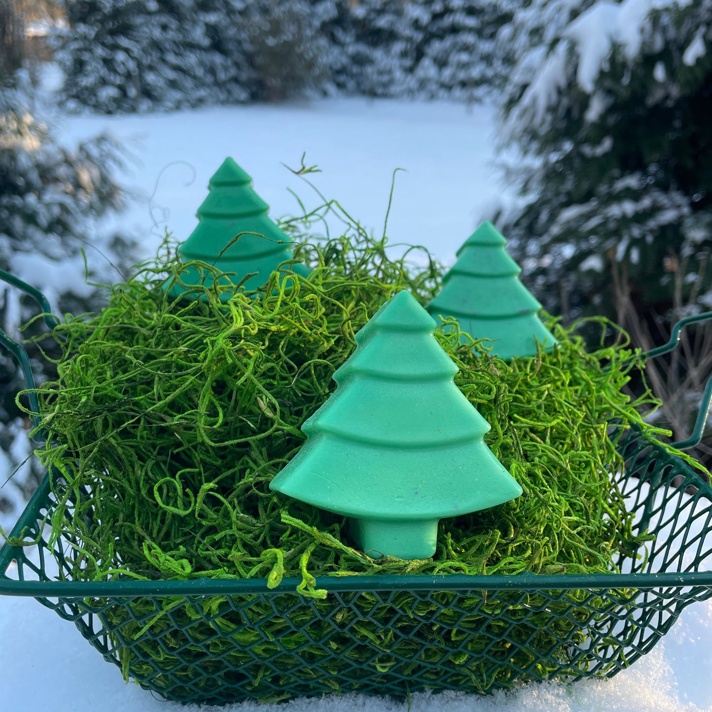 Green decorative wreath with pine tree shapes on a snowy background