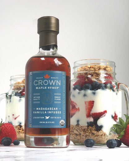Bottle of Crown Maple syrup with a jar of yogurt parfait on a white background