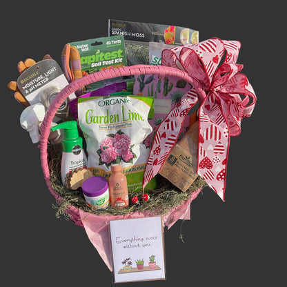 Gardening gift basket with long  handle and various gardening supplies on a dark gray background.  A card sits in front with a succulent plant pun!