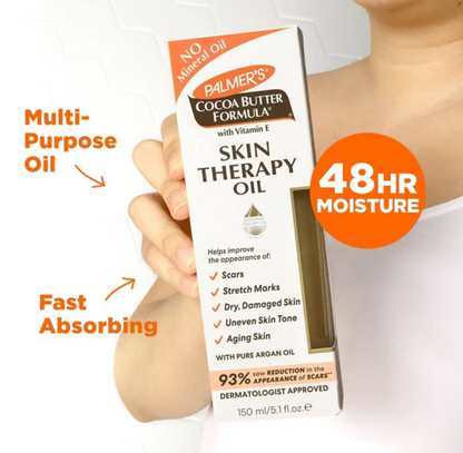 Hand holding a bottle of Palmer’s Skin Therapy Oil with product details on a white background