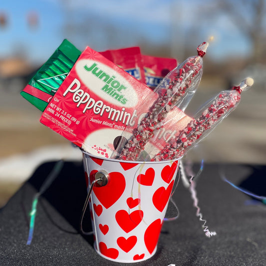Small paper cup with heart pattern filled with peppermint candy on a car hood.