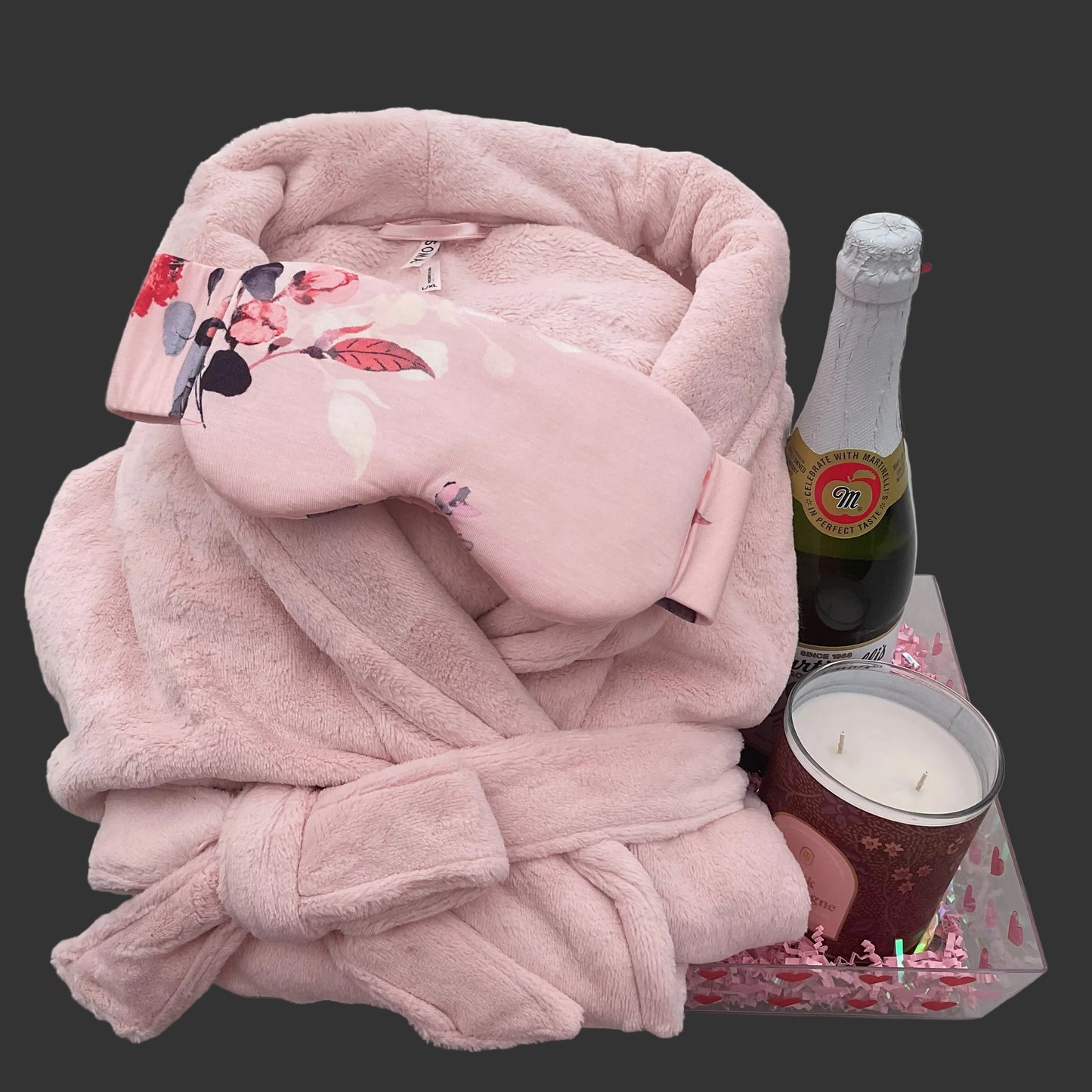 Pink robe, floral-patterned pillow, and bottle of champagne on a surface.
