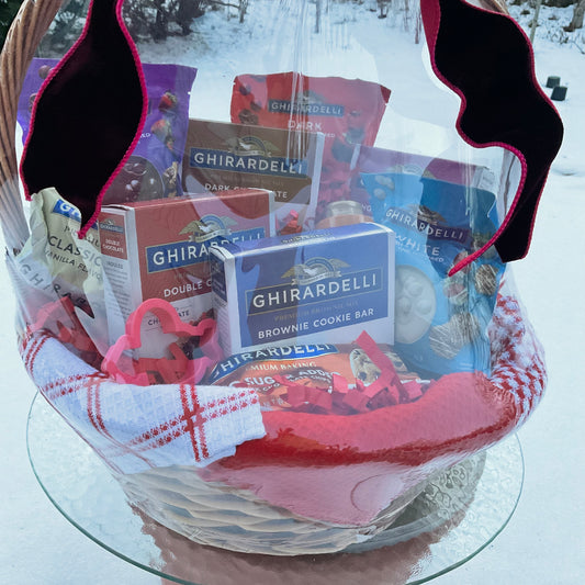Ghirardelli baking mixes and cookie cutters in a decorative basket with a snowy background
