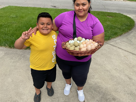A child in a yellow shirt and an adult in a purple shirt holding a basket filled with farm fresh eggs.